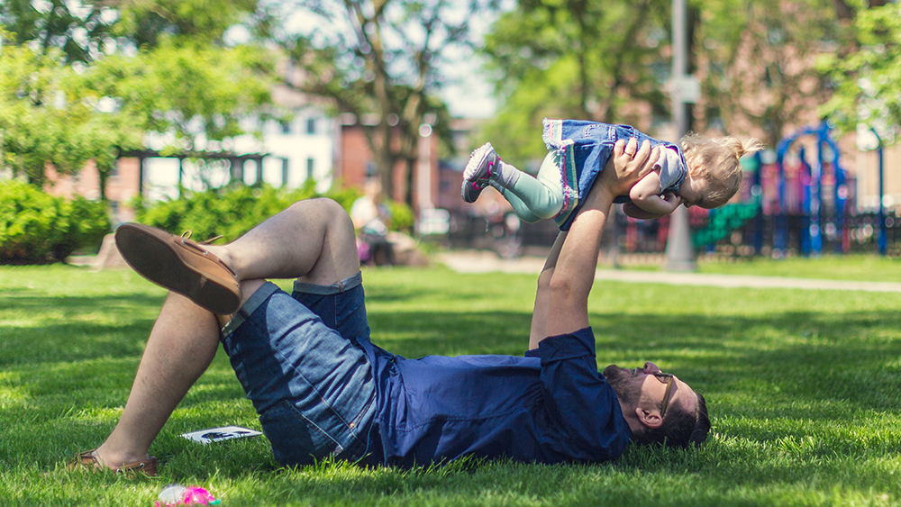 An image of a father and son playing in a sunny park.