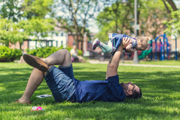 An image of a father and son playing in a sunny park.